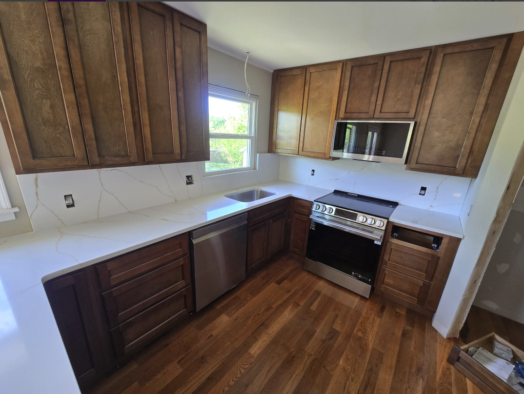 Wood shaker kitchen with white quartz counters and backsplash