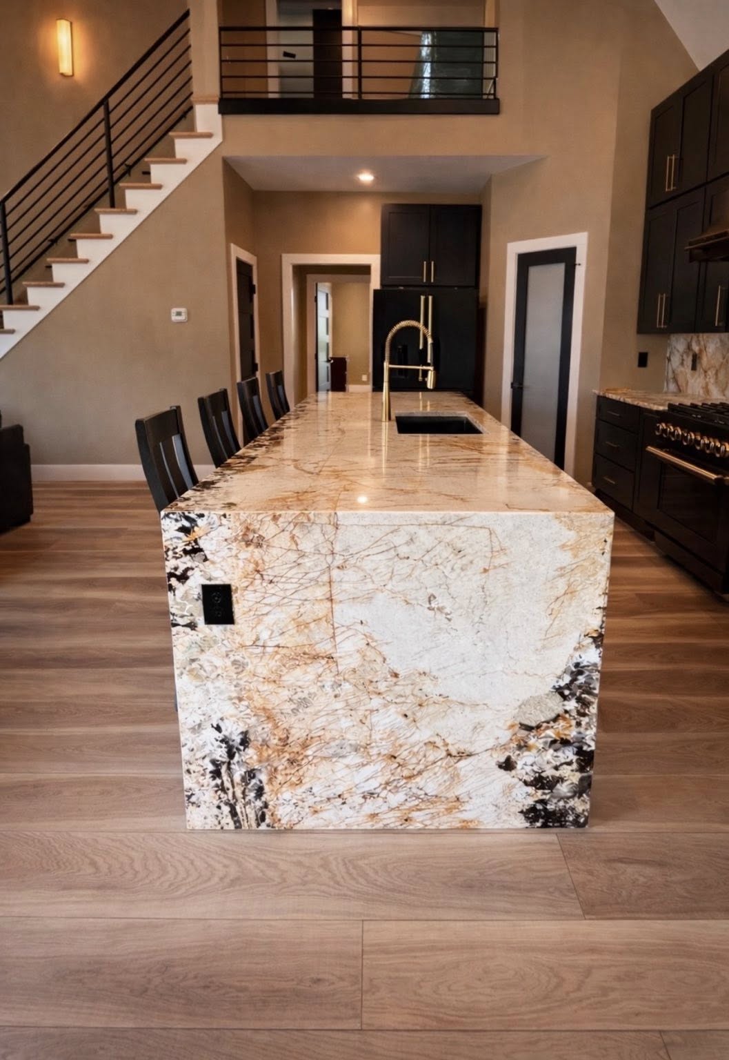 Waterfall granite island in two-story open kitchen