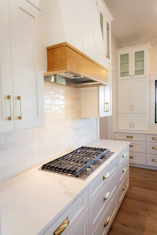 Quartz cooktop detail with wood hood and brass pulls