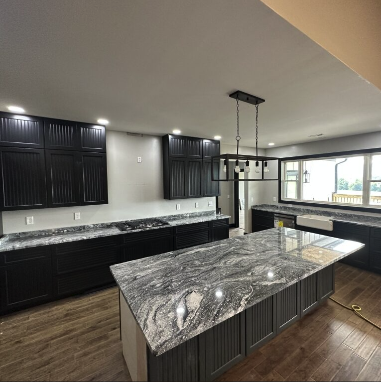 Dark cabinets with veined granite island and perimeter
